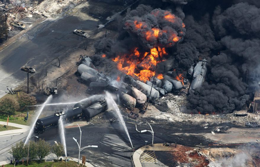 FILE - In this July 6, 2013 file photo, smoke rises from railway cars carrying crude oil after derailing in downtown Lac Megantic, Quebec. American Petroleum Institute President Jack Gerard said Tuesday that the oil and railroad industries are urging federal regulators to allow them as long as seven years to retrofit existing tank cars that transport highly volatile crude oil. (AP Photo/The Canadian Press, Paul Chiasson, File)