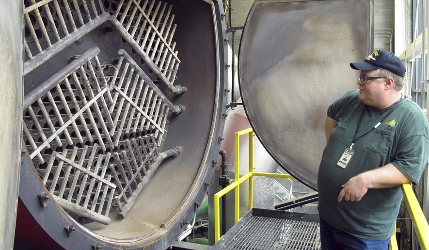 Heating plant supervisor Daniel McLaughlin looks into the fire tube section of a wood-chip-fired boiler Tuesday, Sept. 30, 2014, that will produce steam and hot water to heat state offices and some city buildings in Montpelier, Vt. The $23 million heating system is part of a project to make Montpelier "net zero" by 2030. (AP Photo/Wilson Ring)