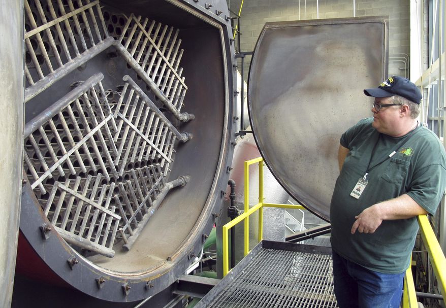 Heating plant supervisor Daniel McLaughlin looks into the fire tube section of a wood-chip-fired boiler Tuesday, Sept. 30, 2014, that will produce steam and hot water to heat state offices and some city buildings in Montpelier, Vt. The $23 million heating system is part of a project to make Montpelier "net zero" by 2030. (AP Photo/Wilson Ring)