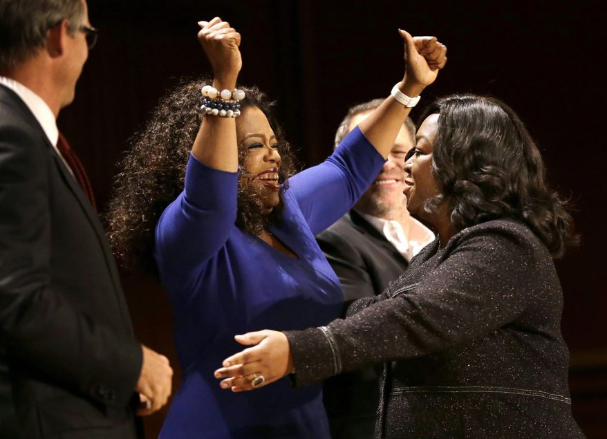 Actor, talk show host and philanthropist Oprah Winfrey, center left, and television producer and writer Shonda Rhimes, right, embrace on stage during the W.E.B. Du Bois medal award ceremonies, Tuesday, Sept. 30, 2014, on the campus of Harvard University, in Cambridge, Mass. The Du Bois Medal is Harvard's highest honor in the field of African and African American Studies. Winfrey and Rhimes both received the medal. (AP Photo/Steven Senne)