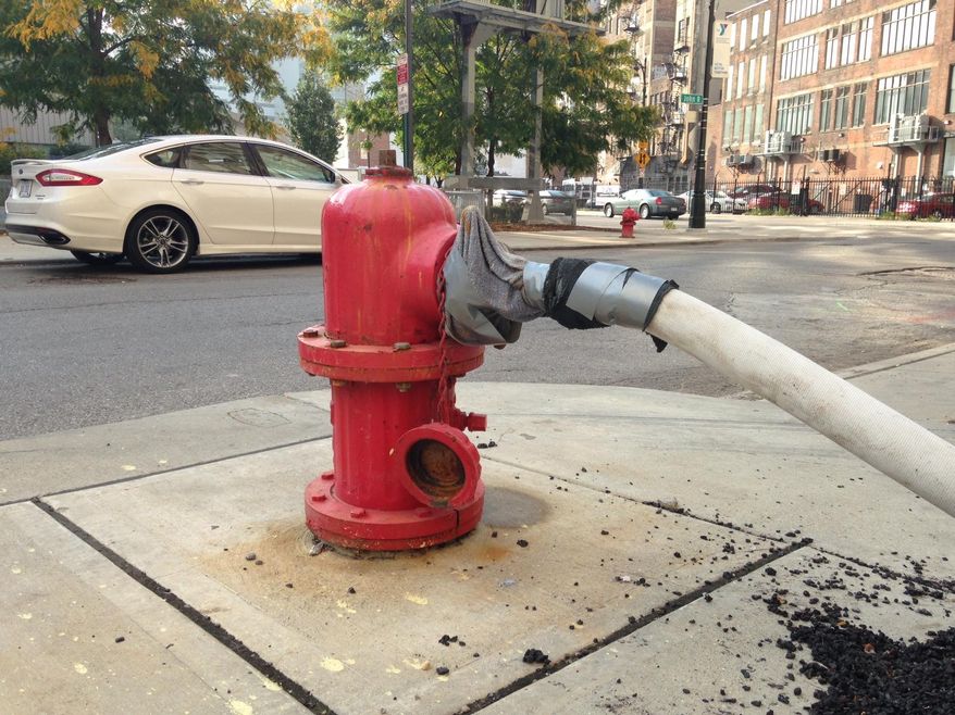 A makeshift water connection to a fire hydrant has been fashioned Thursday, Oct. 2, 2014 outside the 1515 Broadway coffeehouse in Detroit, Mich. A system of plastic pipe, garden hoses, duct tape and towels is providing water service to the coffeehouse and an adjoining jewelry store as city repairs to the water system serving the businesses are on hold, officials said. (AP Photo/Mike Householder)