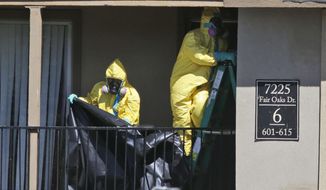 Hazardous material cleaners prepare to hang black plastic outside the apartment in Dallas, Friday, Oct. 3, 2014, where Thomas Eric Duncan, the Ebola patient who traveled from Liberia to Dallas stayed last week. The crew is expected to remove items including towels and bed sheets used by Duncan, who is being treated at an isolation unit at a Dallas hospital. The family living there has been confined under armed guard while being monitored by health officials. (AP Photo/LM Otero)