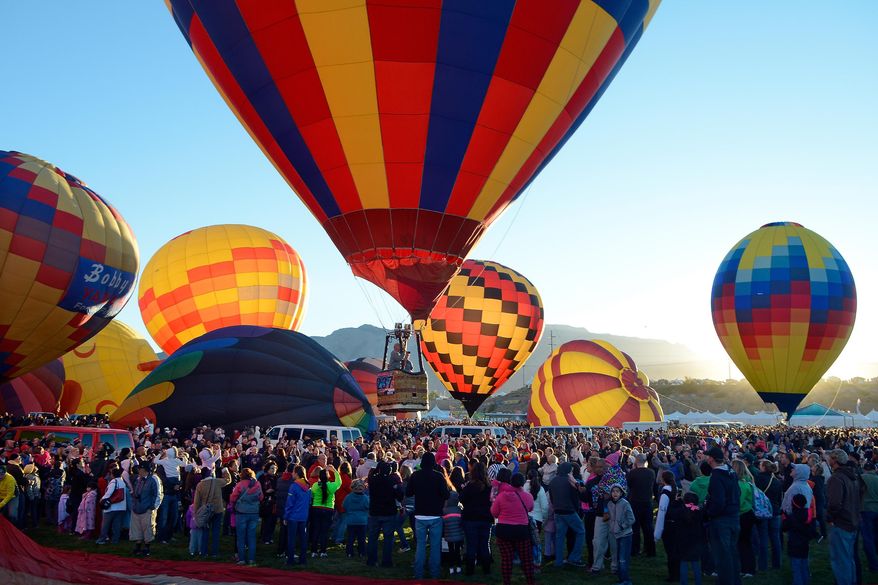 A balloon lifts off over the crowd in the early morning during the annual Albuquerque International Balloon Fiesta in Albuquerque, N.M. Saturday, Oct. 4, 2014. Organizers have equipped all 550 pilots with tablet computers capable of running a mapping application that will enable them to steer clear of the many restricted areas or prohibited zones like airport flight paths, the zoo and other locations. (AP Photo/The Albuquerque Journal, Jim Thompson)