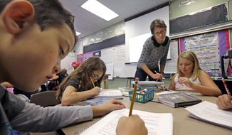 In this Thursday, Oct. 2, 2014, photo, teacher Joy Burke checks on the work of her fifth grade students at John Hay Elementary school in Seattle. (AP Photo/Elaine Thompson) ** FILE **