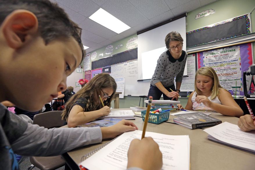 In this Thursday, Oct. 2, 2014, photo, teacher Joy Burke checks on the work of her fifth grade students at John Hay Elementary school in Seattle. (AP Photo/Elaine Thompson) ** FILE **