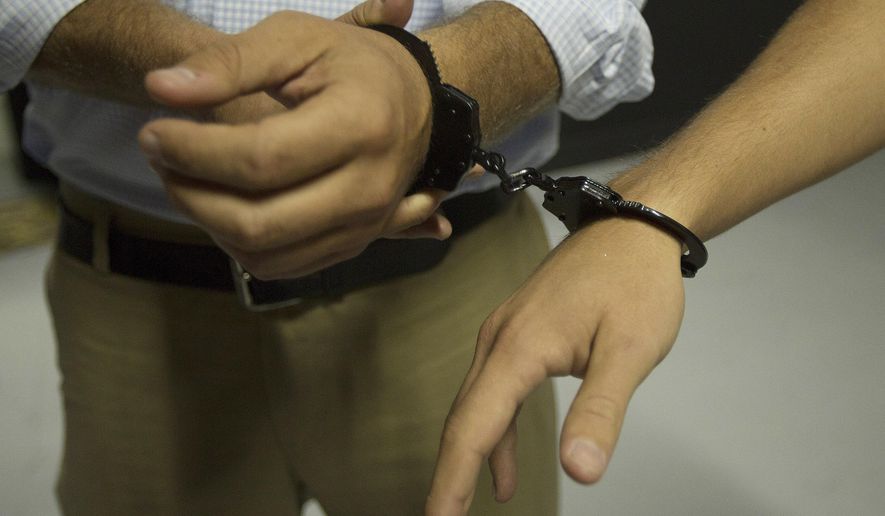 In this Sept. 22, 2014, photo, two people are handcuffed together as they start to play a game at Escape the Quest in Miami Beach, Fla.  (AP Photo/J Pat Carter) ** FILE **