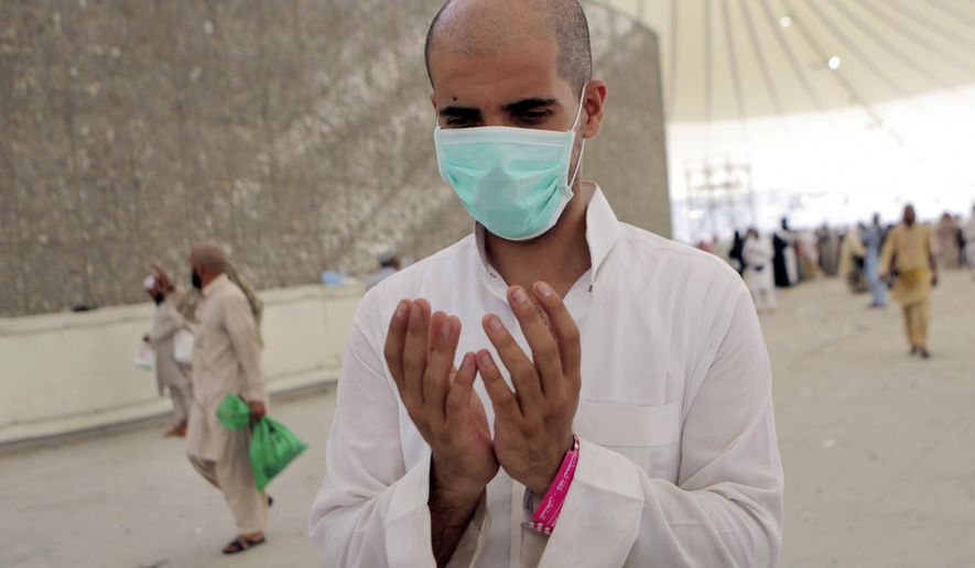 A Muslim pilgrim wearing a medical mask prays after casting pebbles in a symbolic stoning of the devil, during the annual pilgrimage, known as the hajj, in Mina, a desert tent city just outside the holy city of Mecca Saudi Arabia, Monday, Oct. 6, 2014. Male pilgrims shaved their heads as a sign of renewal. More than 2 million pilgrims took part this year. (AP Photo/Khalid Mohammed)