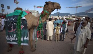 A man parades a camel with a banner that reads, &quot;go Nawaz go,&quot; outside a parliament building where anti-government protesters are gathered, on Eid al-Adha, or &quot;Feast of Sacrifice,&quot; in Islamabad, Pakistan, Monday, Oct. 6, 2014.  On the start of Eid holiday, Muslims slaughter sheep, cattle and other livestock, and give part of the meat to the poor. The holiday began Monday in Pakistan. (AP Photo/B.K. Bangash) ** FILE ** 