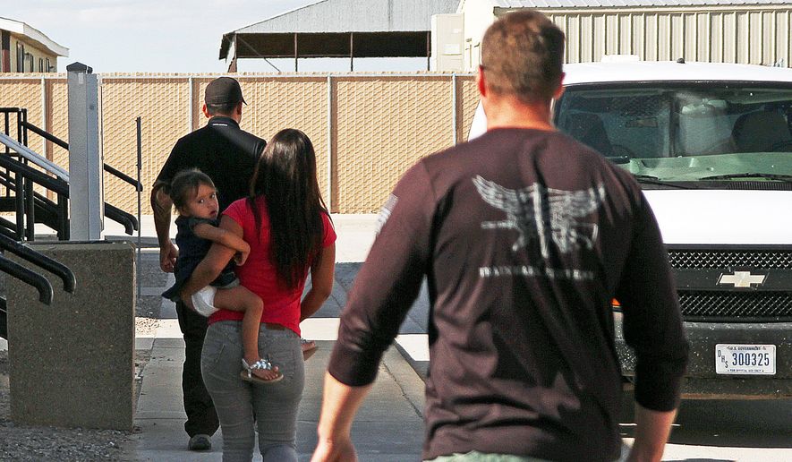 FILE- In this Sept. 10, 2014 file photo, a woman and child are escorted to a van by detention facility guards inside the Artesia Family Residential Center, a federal detention facility for undocumented immigrant mothers and children in Artesia, N.M, A surge of cases involving immigrants from Central America has backed up federal courts and U.S. Immigration and Customs Enforcement. The cases have been moved to Denver by judges in Arlington, Va. Officials say it makes more sense to hold the proceedings in the same time zone as the detention center. Hearings are being held by video from Artesia, N.M. starting on Monday, Sept. 29. (AP Photo/Juan Carlos Llorca, File)