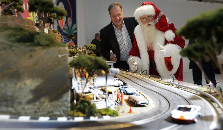 Brady Smith, as Santa Claus, right, and David Beattie check out the Slot Mods USA Ultimate Slot Car Raceway during the unveiling of the Neiman Marcus Christmas Book, Tuesday, Oct. 7, 2014, in Dallas. The cost of the 1:32 scale model race track is $300,000. (AP Photo/LM Otero)