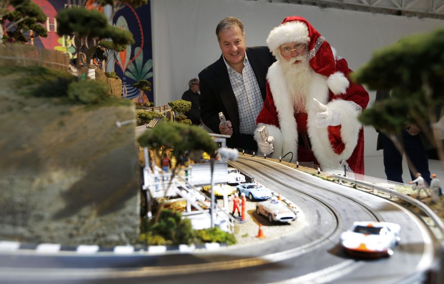 Brady Smith, as Santa Claus, right, and David Beattie check out the Slot Mods USA Ultimate Slot Car Raceway during the unveiling of the Neiman Marcus Christmas Book, Tuesday, Oct. 7, 2014, in Dallas. The cost of the 1:32 scale model race track is $300,000. (AP Photo/LM Otero)