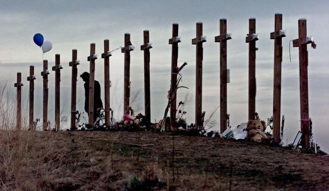 FILE - This April 28, 1999 file photo shows a woman standing among 15 crosses posted on a hill above Columbine High School in Littleton, Colo., in remembrance of the 15 people who died during a school shooting on April 20. A play about the Columbine High School massacre written from the perspective of the two teen shooters will make its world premiere in New York next month, penned by a playwright who was 9 at the time of the killings and calls it &amp;quot;a watershed moment.&amp;quot; (AP Photo/Eric Gay, file)