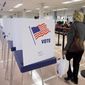 A woman walks past voting booths at the Cuyahoga County Board of Elections in Cleveland, Ohio, on Tuesday, Oct. 7, 2014, in this file photo. (AP Photo/Mark Duncan) **FILE**