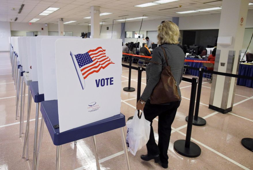 A woman walks past voting booths at the Cuyahoga County Board of Elections in Cleveland, Ohio, on Tuesday, Oct. 7, 2014, in this file photo. (AP Photo/Mark Duncan) **FILE**
