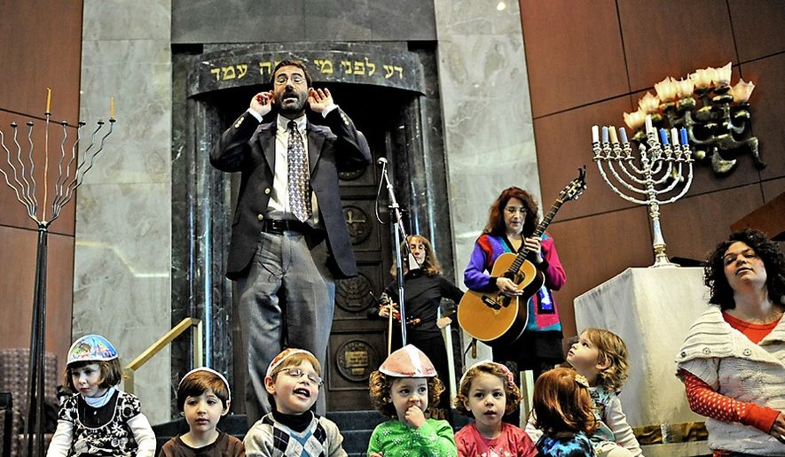 Rabbi Gil Steinlauf leads a group of children in song Friday during a celebration of the first night of Hanukkah at Adas Israel Congregation in Washington, D.C., in 2010. The rabbi has now come out as gay. (Joseph Silverman/The Washington Times)