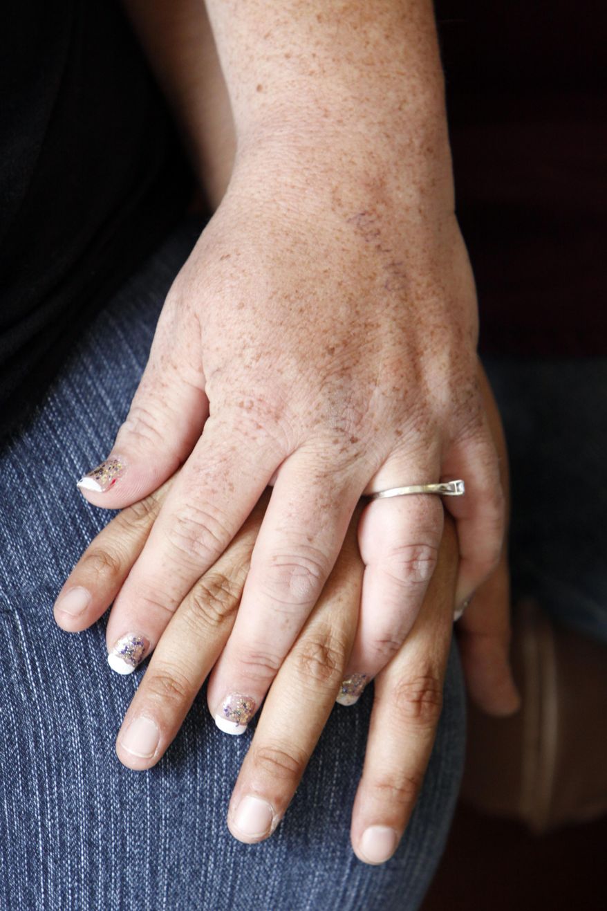 Aimee McCarter and Jen Kozushko hold hands as they wait for the Clerk of the District Court office to open for the afternoon to apply for a marriage license on Tuesday, Oct. 7, 2014, at the Reno County Courthouse in Hutchinson, Kan. The couple was informed later in the day of the application's denial. (AP Photo/The Hutchinson News, Lindsey Bauman)