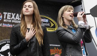 Sadie Robertson of &quot;Duck Dynasty&quot; holds her hand to her heart as her aunt Missy Robertson sings the national anthem before the start of a rain-delayed NASCAR Sprint Cup Series auto race at Texas Motor Speedway in Fort Worth. (AP Photo/Mike Stone)