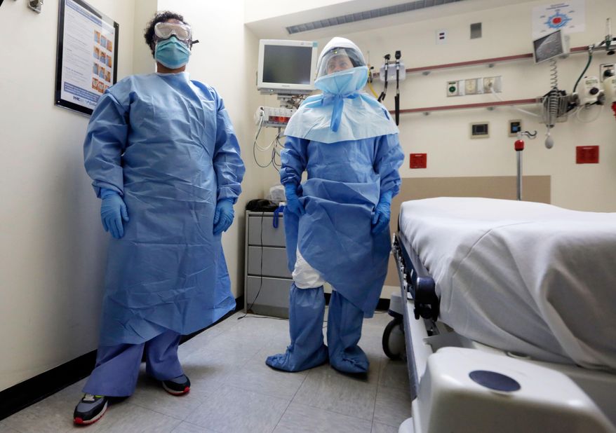 Bellevue Hospital nurse Belkys Fortune, left, and Teressa Celia, Associate Director of Infection Prevention and Control, pose in protective suits in an isolation room, in the Emergency Room of the hospital, during a demonstration of procedures for possible Ebola patients, Wednesday, Oct. 8, 2014. The U.S. government plans to begin taking the temperatures of travelers from West Africa arriving at five U.S. airports, including the New York area&#39;s JFK International and Newark Liberty International, as part of a stepped-up response to the Ebola epidemic. (AP Photo/Richard Drew)