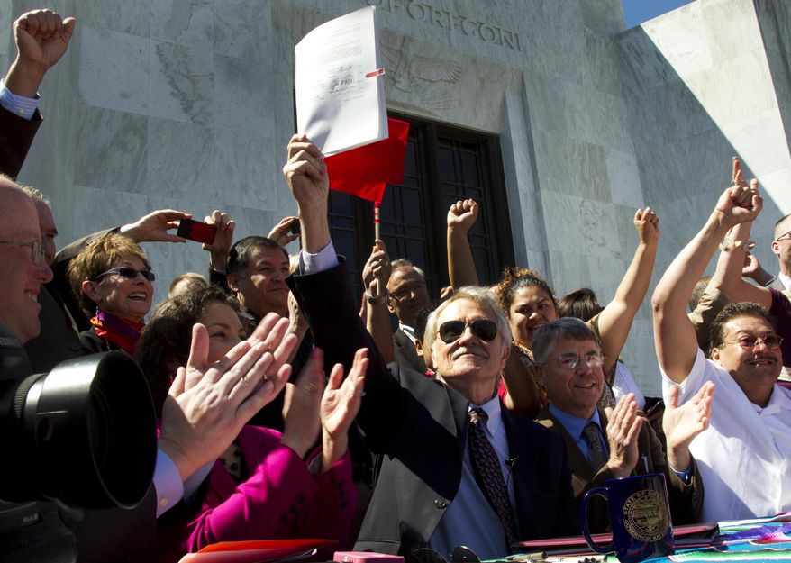 FILE - In this May 1, 2013, file photo, Oregon Gov. John Kitzhaber holds up Senate Bill 833, which authorizes driver's cards for those without the documents to obtain regular driver's licenses, after signing it into law on the steps of the State Capitol in Salem, Ore. Around the country, Oregon is among some states that have been granting more privileges to immigrants as immigration reform fails to make any headway in Congress. (AP Photo/The Oregonian, Beth Nakamura, File)