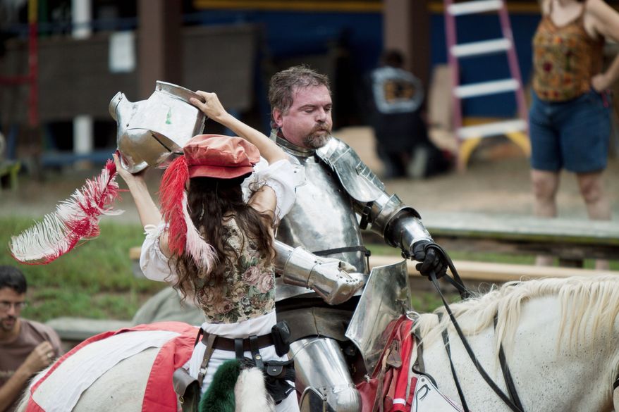 One of the Renaissance Festival's fair maidens helps Leland Coleman get his armor on before heading into "combat" with the Free Lancers. (Pratik Shah/The Washington Times)