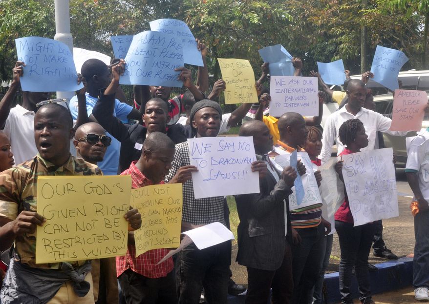 In this photo taken Thursday, Oct. 9, 2014, Liberians stage a protest outside the National Assembly against the government not doing enough to fight Ebola virus in Monrovia, Liberia. The presidents of three Ebola-stricken West African nations made urgent pleas for money, doctors and hospital beds Thursday and representatives of nations gathered for financial meetings promised more help. (AP Photo/Abbas Dulleh)