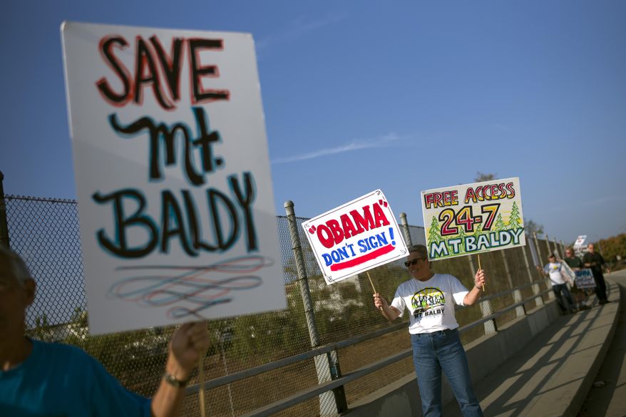 Protesters hold signs to oppose President Barack Obama's designation of the San Gabriel Mountains as a national monument before Obama's visit to Frank G. Bonelli Regional Park Friday, Oct. 10, 2014, in San Dimas, Calif. (AP Photo/Jae C. Hong)