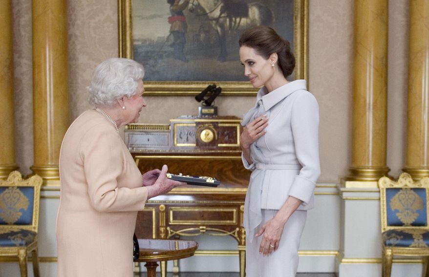 U.S. actress Angelina Jolie, right, is presented with the Insignia of an Honorary Dame Grand Cross of the Most Distinguished Order of St. Michael and St. George by Britain's Queen Elizabeth II at Buckingham Palace, London, Friday, Oct. 10, 2014. Jolie received an honorary damehood (DCMG) for services to U.K. foreign policy and the campaign to end war zone sexual violence. (AP Photo/Anthony Devlin, pool)