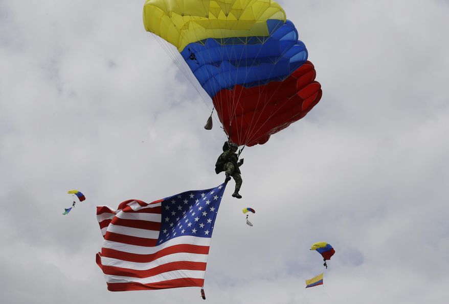 Colombian airborne troops parachute in a show of military exercises at the Tolemaida military base during a visit by U.S. Defense Secretary Chuck Hagel, in Melgar, Colombia, Friday, Oct. 10, 2014. Colombia's was Hagel's first stop on his six-day, three-country trip to South America. Hagel will also travel to Chile and Peru, where he will attend a conference of defense ministers from the Americas. (AP Photo/Fernando Vergara)