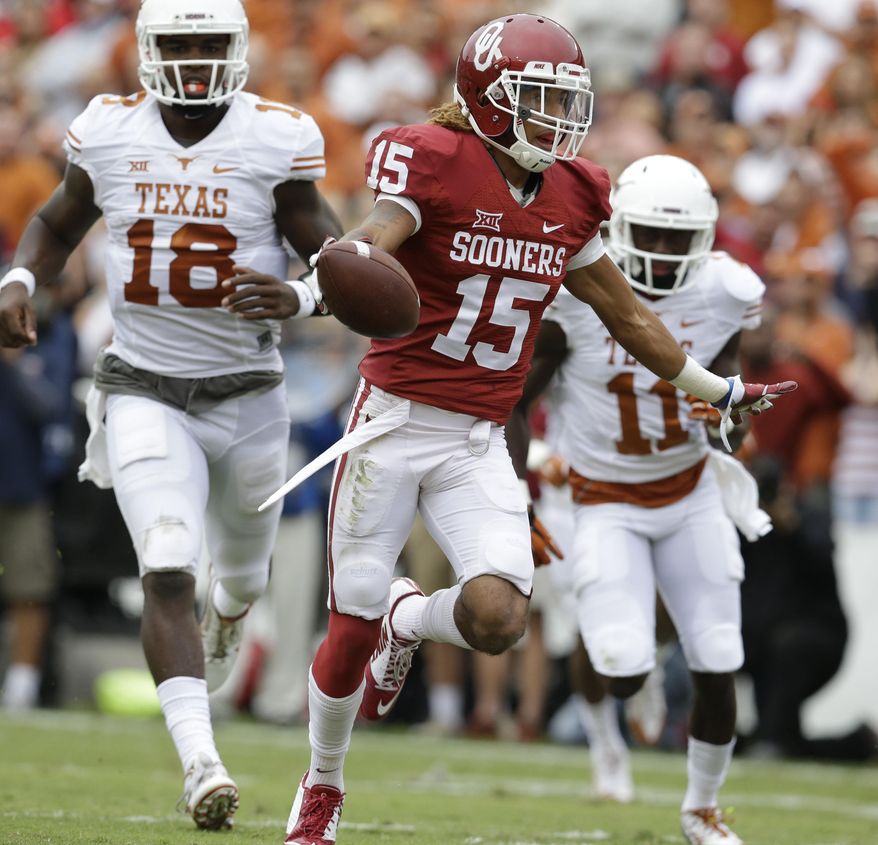 Oklahoma cornerback Zack Sanchez (15) celebrates scoring a touchdown after intercepting a pass against Texas wide receiver Jacorey Warrick (11) and quarterback Tyrone Swoopes (18) during the first half of an NCAA college football game at the Cotton Bowl, Saturday, Oct. 11, 2014, in Dallas. (AP Photo/LM Otero)