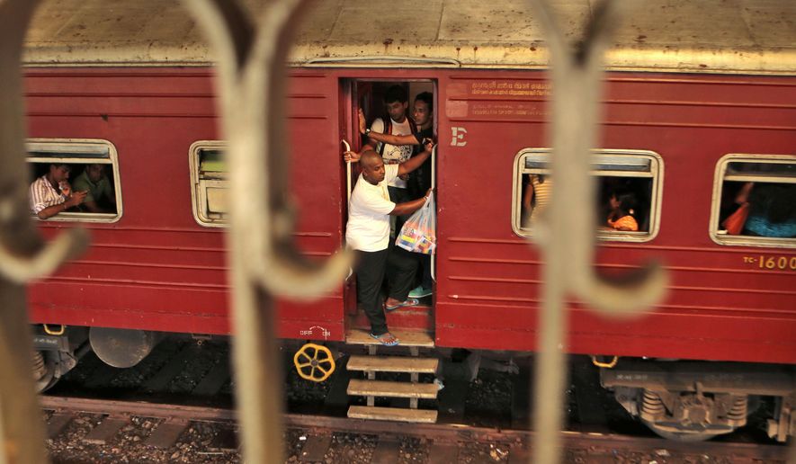People ride a train that is about to reach Fort railway station in Colombo, Sri Lanka, Saturday, Oct. 11, 2014. The "Queen of Jaffna," a once-popular train linking the ethnic Tamil's northern heartland to the rest of Sri Lanka before a bloody civil war cut the link 24 years ago, chugs back into service next week, reinforcing the government's authority in a region once controlled by Tamil rebels. President Mahinda Rajapaksa will inaugurate service along the 400-kilometer (250-mile) route between Jaffna and Colombo, the capital, in a ceremony Monday. (AP Photo/Eranga Jayawardena)