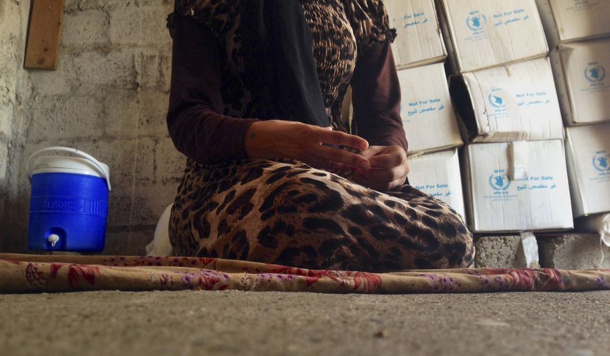 In this photo taken Wednesday, Oct. 8, 2014, a 15-year-old Yazidi girl captured by the Islamic State group and forcibly married to a militant in Syria sits on the floor of a one-room house she now shares with her family after escaping in early August, while speaking in an interview with The Associated Press in Maqluba, a hamlet near the Kurdish city of Dahuk, 260 miles (430 kilometers) northwest of Baghdad, Iraq. (AP Photo/Dalton Bennett)