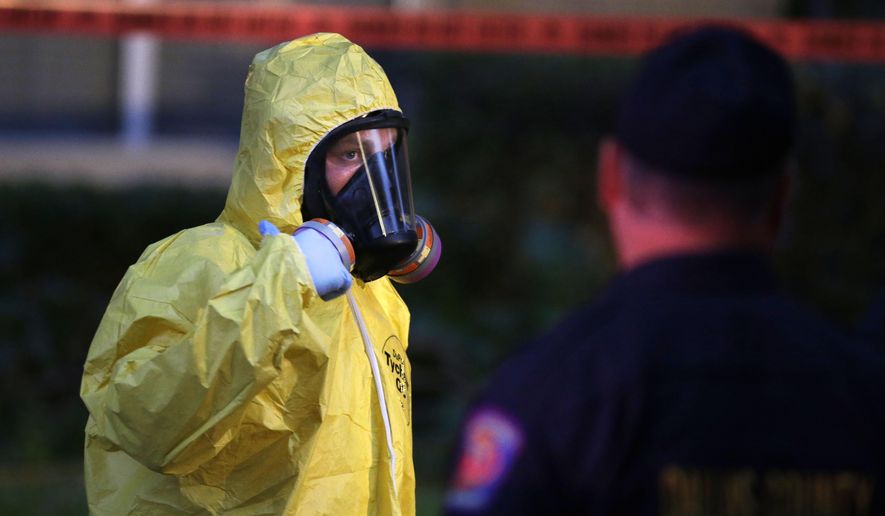 A hazmat worker looks up while finishing up cleaning outside an apartment building of a hospital worker, Sunday, Oct. 12, 2014, in Dallas. The Texas health care worker, who was in full protective gear when they provided hospital care for Ebola patient Thomas Eric Duncan, who later died, has tested positive for the virus and is in stable condition, health officials said Sunday. (AP Photo/LM Otero)