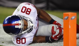 New York Giants wide receiver Victor Cruz holds his knee after going down while chasing a pass against the Philadelphia Eagles during the second half of an NFL football game, Sunday, Oct. 12, 2014, in Philadelphia. (AP Photo/Matt Rourke)