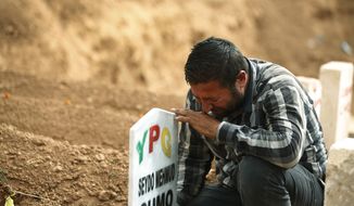 FILE - In this Saturday, Oct. 11, 2014 file photo, Kurdish Ali Mehmud mourns at the grave of his brother Seydo Mehmud &#39;Curo&#39;, a Kurdish fighter, who was killed in the fighting with the militants of the Islamic State group in Kobani, Syria, and was buried at a cemetery in Suruc, Turkey. No one contests that the U.S.-led coalition has conducted more than 40 airstrikes against the militants besieging Kobani, nor that Turkey has granted refuge to more than 200,000 people who have flooded across the border to escape the offensive. But Kurds say that both countries - and the international community in general - should be doing more to help save Kobani from the fanatical militants who have massacred and beheaded their enemies across Syria and Iraq. (AP Photo/Lefteris Pitarakis, File)