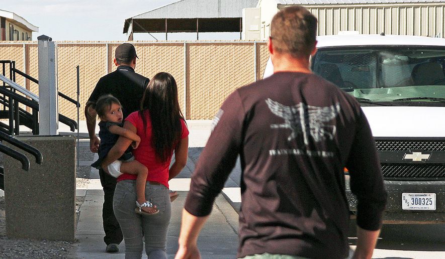 FILE- In this Sept. 10, 2014 file photo, a woman and child are escorted to a van by detention facility guards inside the Artesia Family Residential Center, a federal detention facility for undocumented immigrant mothers and children in Artesia, New Mexico. The facility is now releasing more detainees rather than deporting them, according to Artesia Mayor Phillip Burch. (AP Photo/Juan Carlos Llorca, File)