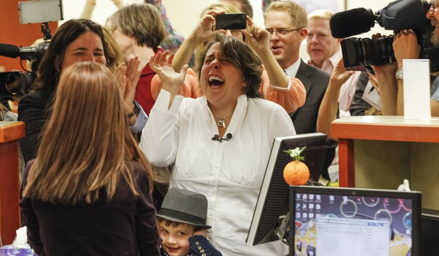 Shelia Robertson, center, and her son Bridger, bottom center, react at as the county recorder opens at 10 a.m. to issue same-sex marriage licenses at the Ada County Courthouse in Boise, Idaho, on Wednesday, Oct. 15, 2014. Robertson and her partner Andrea Altmayer, left, partially hidden, were two of the eight women who sued over Idaho's marriage ban,. (AP Photo/Otto Kitsinger)