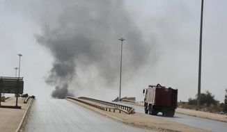 A fire truck drives towards smoke caused by an attack by Islamist militias during clashes with forces led by renegade Libyan Gen. Khalifa Hifter in Benghazi, Libya, Wednesday, Oct. 15, 2014. Islamist militias fought Wednesday with forces loyal to Hifter, who vows to seize the eastern city of Benghazi, as a top militia commander accused Egypt of bombing his positions with warplanes. (AP Photo/Mohammed el-Sheikhy)
