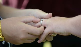 Brittany Dickerson, left, places a ring on Ashley Owens&#39; hand as they&#39;re married by the Rev. Bud Liptrap, Wednesday, Oct. 15, 2014, at Harry Barry Park in Twin Falls, Idaho. (AP Photo/The Times-News, Drew Nash) ** FILE **