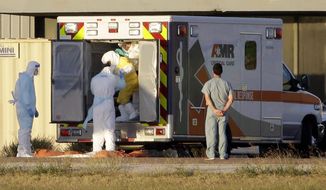 Medical staff in protective gear escort Nina Pham, exiting the ambulance, to a nearby aircraft at Love Field, Thursday, Oct. 16, 2014, in Dallas. Pham, a nurse at Texas Health Presbyterian Hospital Dallas, was diagnosed with the Ebola virus after caring for Thomas Eric Duncan who died of the same virus. (AP Photo/Tony Gutierrez)