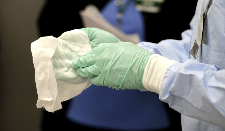 Registered nurse Keene Roadman, dressed in personal protective equipment, demonstrates bleach wiping the inner layer of gloves, after the outer gloves are removed during a training class at the Rush University Medical Center, Thursday, Oct. 16, 2014, in Chicago. With hospital workers increasingly in the spotlight of concern over the spread of the Ebola virus, the hospital held a training session for a team of medical professionals with expertise in intensive care and infection control. (AP Photo/Charles Rex Arbogast)