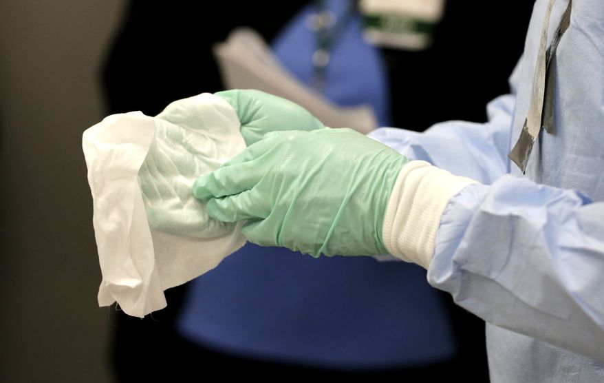 Registered nurse Keene Roadman, dressed in personal protective equipment, demonstrates bleach wiping the inner layer of gloves, after the outer gloves are removed during a training class at the Rush University Medical Center, Thursday, Oct. 16, 2014, in Chicago. With hospital workers increasingly in the spotlight of concern over the spread of the Ebola virus, the hospital held a training session for a team of medical professionals with expertise in intensive care and infection control. (AP Photo/Charles Rex Arbogast)