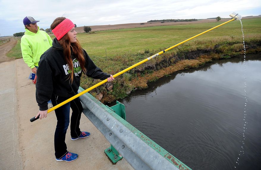 ADVANCE FOR MONDAY OCT. 20 - In this Oct. 9, 2014 photo, Castlewood High School student Morgan Artz rinses a bottle while collecting water from Skunk Creek as Kevin Christenson, a natural resources technician with East Dakota Water Development District, looks on near Lyons, S.D. The city of Sioux Falls plans to spend more than $1 million to pay farmers to keep their cows out of the Big Sioux River and its tributaries. (AP Photo/The Argus Leader, Jay Pickthorn) NO SALES