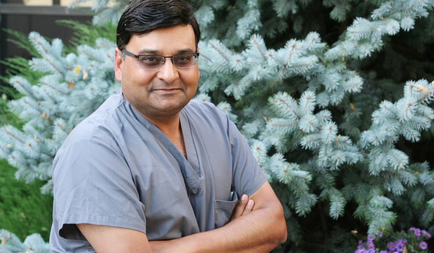 In this photo taken on Sept. 30, 2014, Dr. Mukesh Garg poses for a photo outside Mary Lanning Memorial Healthcare hospital in Hasting, Neb. (AP Photo/The Hastings Tribune, John Huthmacher)