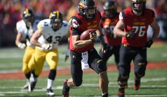Maryland quarterback C.J. Brown, center, runs with the ball against Iowa during the first half of an NCAA college football game, Saturday, Oct. 18, 2014, in College Park, Md. Maryland won 38-31. Also seen is Maryland offensive lineman Michael Dunn (76). (AP Photo/Nick Wass)