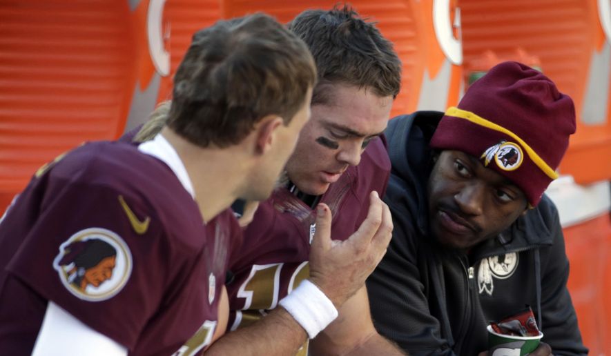 Washington Redskins quarterback Kirk Cousins, left, sits on the bench with quarterback Colt McCoy and quarterback Robert Griffin III, right, during the second half of an NFL football game against the Tennessee Titans, Sunday, Oct. 19, 2014, in Landover, Md. The Redskins won 19-17. (AP Photo/Pablo Martinez Monsivais)