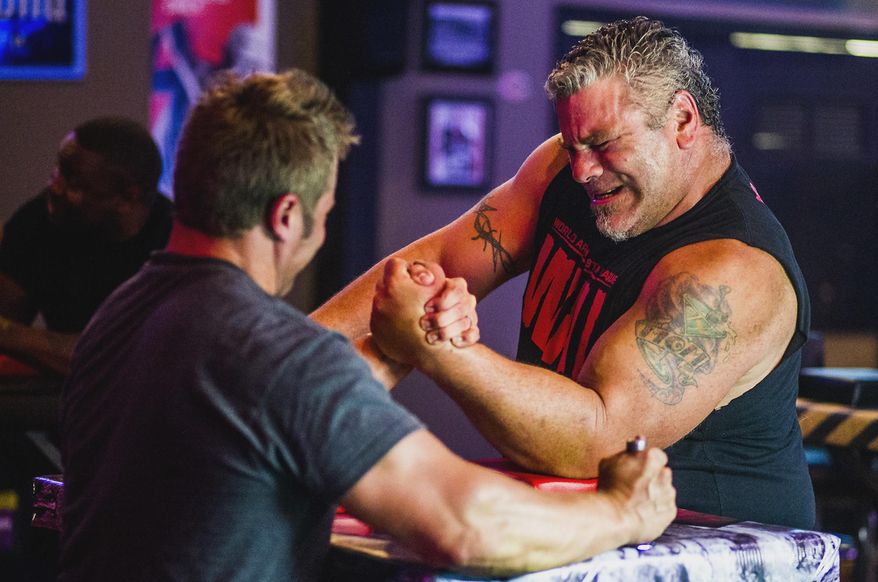 In this Sept. 17, 2014 photo, Kent DaMore, right, of McHenry, Ill., arm wrestles with Chris Gellings, of Crystal Lake, Ill., during an arm wrestling lesson at Long Shot Sports Pub in Lakemoor, Ill. Since the AMC reality television show “Game of Arms” premiered in February to a record 1 million viewers, arm wrestling has experienced a bit of a resurgence, both in McHenry County and elsewhere across the country. (AP Photo/Northwest Herald, Kyle Grillot) MANDATORY CREDIT