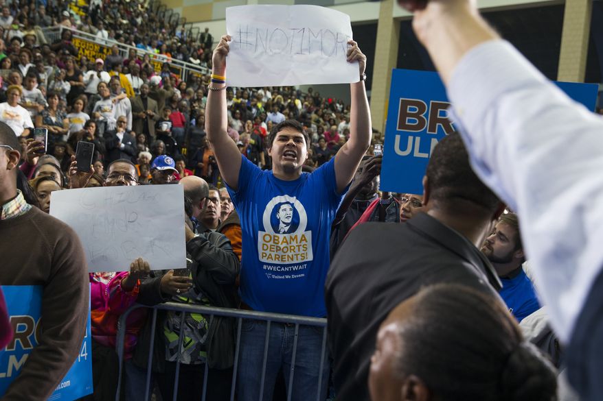 A demonstrator shouting about immigration policy interrupts President Barack Obama during a campaign rally for Maryland gubernatorial candidate Anthony Brown at Wise High School, on Sunday, Oct. 19, 2014, in Upper Marlboro, Md. (AP Photo/Evan Vucci)  