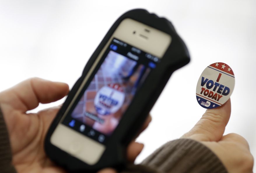 Jennifer Laird photographs her "I Voted Today" sticker after casting her ballot on the first day of early voting, Monday, Oct. 20, 2014 photo, in Miami. Florida Republican Governor Rick Scott is running against Democrat Charlie Crist in the gubernatorial election Nov. 4. (AP Photo/Lynne Sladky)