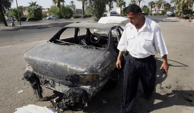 FILE - In this Sept. 25, 2007 file photo, an Iraqi traffic policeman inspects a car destroyed by a Blackwater security detail in al-Nisoor Square in Baghdad, Iraq. A federal jury reached a verdict Wednesday in the case of four former Blackwater security guards on trial in the shootings of more than 30 Iraqi citizens in the heart of Baghdad. The verdicts were to be read during a late-morning court session. The shootings triggered an international uproar over the role of defense contractors in urban warfare. (AP Photo/Khalid Mohammed, File)