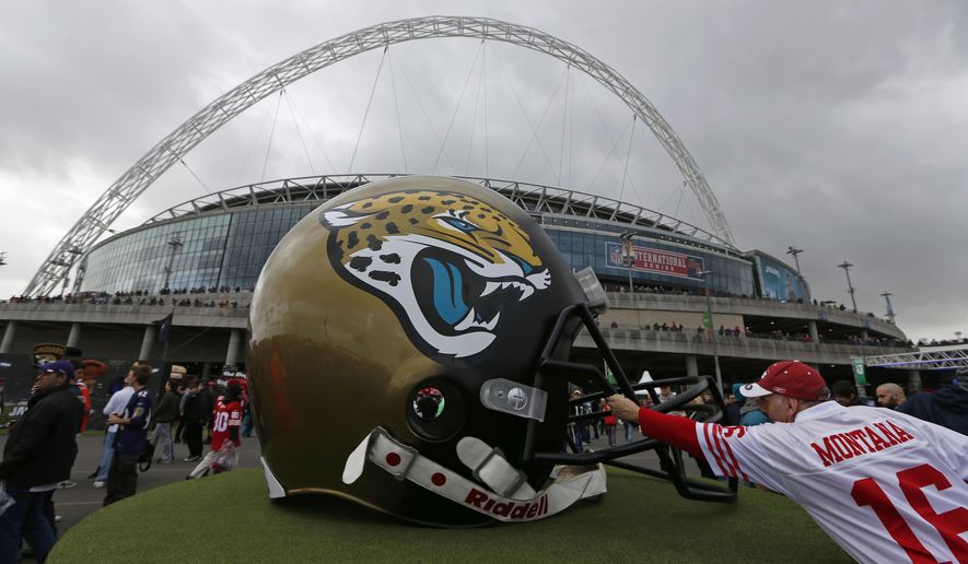 A 49ers supporter reaches out to touch a giant Jaguars helmet as fans arrive at Wembley Stadium in London to watch the NFL football game between San Francisco 49ers and Jacksonville Jaguars, Sunday, Oct. 27, 2013. (AP Photo/Sang Tan)